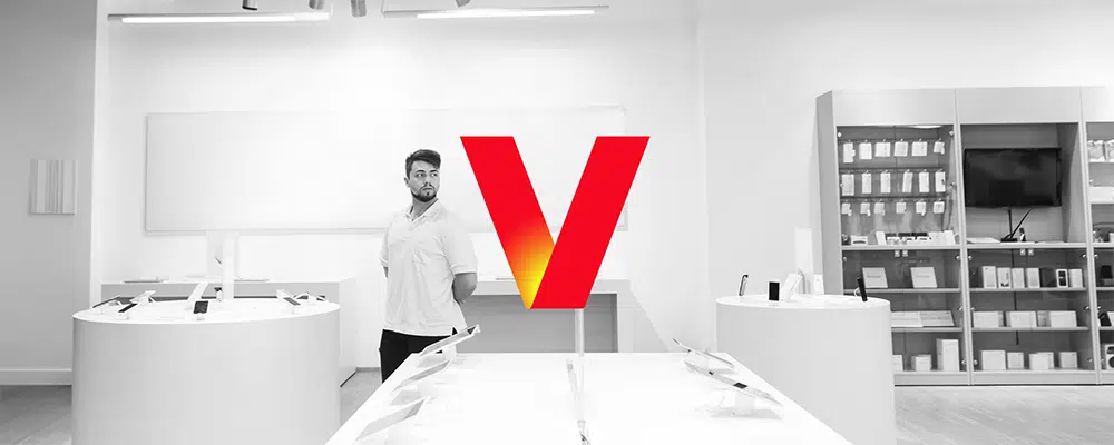 Guy standing in phone store looking for a new phone