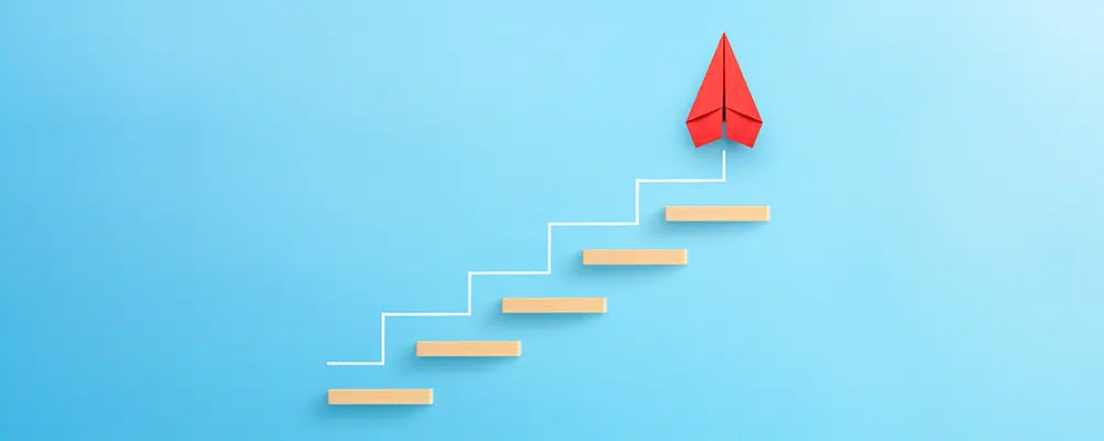 Wooden block stacking as step stair with red paper plane on blue background, Ladder of success in business growth concept, copy space