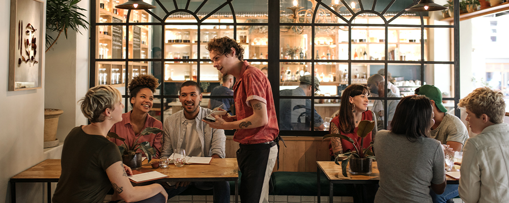 Waiter taking orders from customers sitting in a bistro