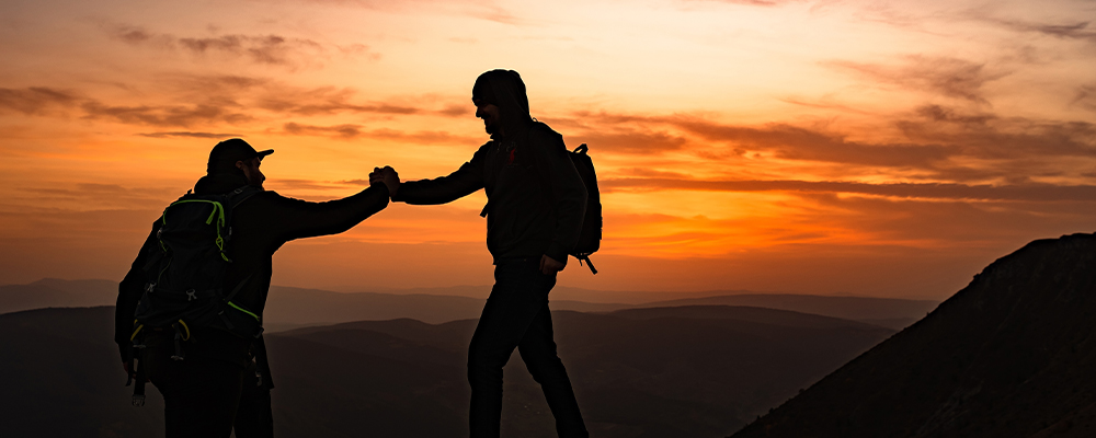 Hiking team people helping each other friend giving a helping hand while climbing up on the mountain rock adventure travel concept of support trust teamwork success.