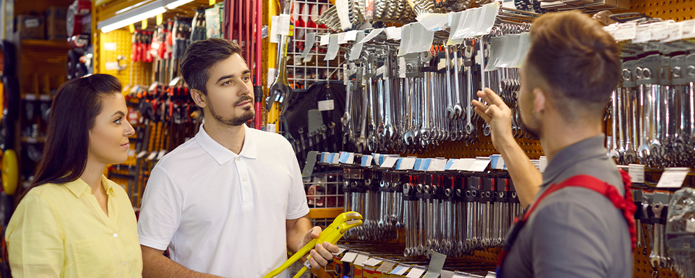 Seller advises couple of customers on type of spanners in building materials store.